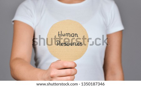 Young women  showing   round cardboard paper     with handwritten text  - Human Resources, .