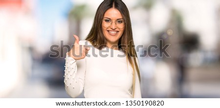 Pretty woman with glasses points finger at you with a confident expression at outdoors