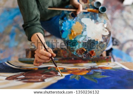 Top view of attractive woman hands drawing amazing picture on canvas in modern cozy art workshop