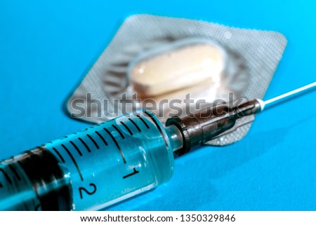 medical syringe and pills on blue background, medicine theme