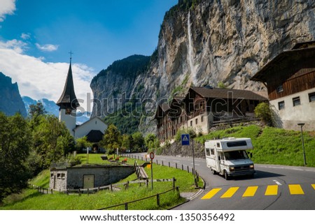 Motorhome cruising Lauterbrunnen valley, waterfall in background, old motorhome, church cross, Switzerland