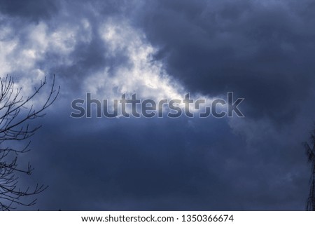 Dark blue sky with glimpses of light and tree branches