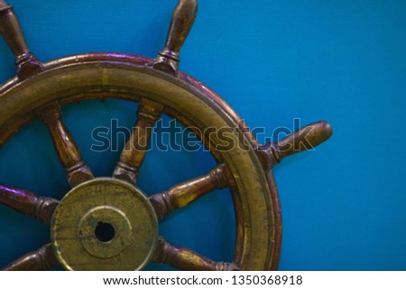 Part of Old wooden ship wheel on blue background with copy space