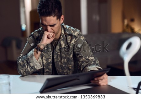 Army soldier experiencing emotional pain while holding framed picture and feeling homesick.
