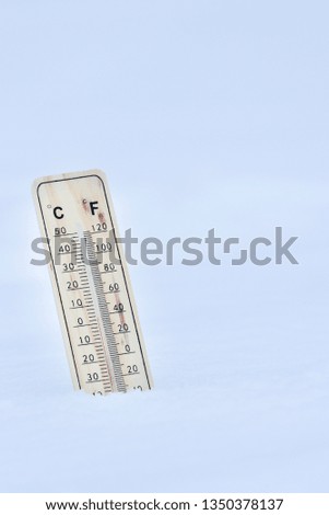 Winter time. thermometer on snow shows low temperatures in celsius or fahreneheit. 