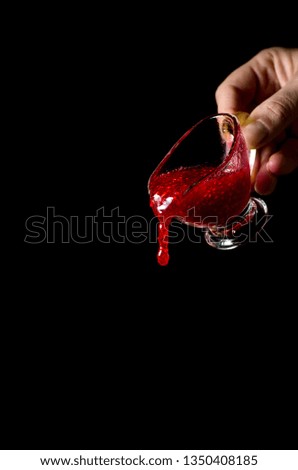 Fresh and tasty raspberry jam in nice glass souceboat on black background in woman hand