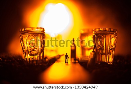 Abstract alcoholism concept. Silhouette of a man standing in the middle of the road on a misty night with giant glasses filled with alcoholic beverage. Creative artwork decoration