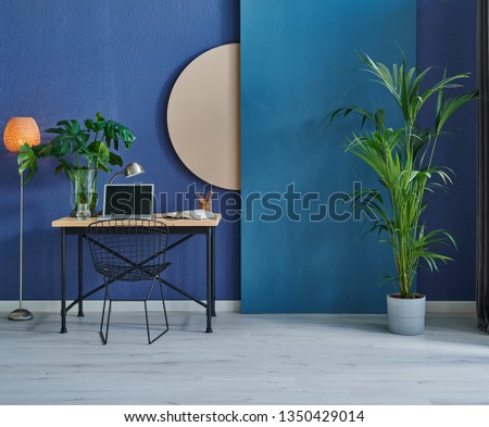 Modern dark blue stone wall, textured wall, blue decorative wall, chair vase of plant and table interior concept. Home wall background. laptop and technology interior room.