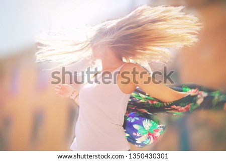 Attractive happy young woman in white t shirt flying hair enjoying her free time at sunset outdoor. Beauty fit teen girl portrait at summer. Freedom lifestyle springtime concept Sun glow on background
