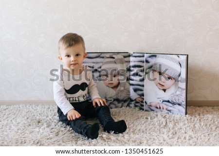 Cute baby sitting on the background of a large stylish photo book with your photos