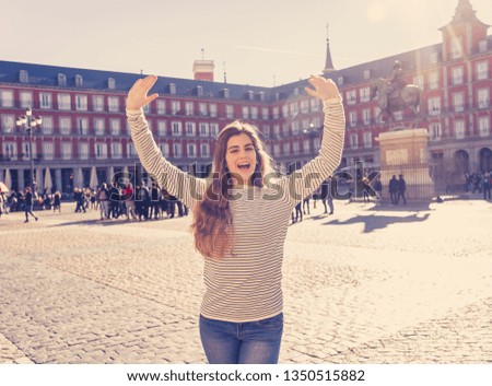 Beautiful happy young woman excited having fun in Plaza Mayor Madrid, Spain. Looking cheerful and delighted enjoying sightseeing and posing for picture. In tourism, European city and travel in Europe.