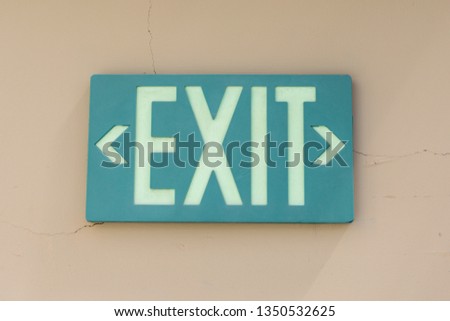 Exit sign that is green and on a tan wall