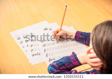 Child practicing cursive writing. Royalty-Free Stock Photo #1350535511