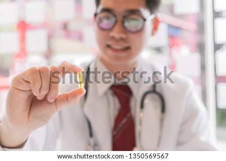Male doctor holding fish oil pill in hand.