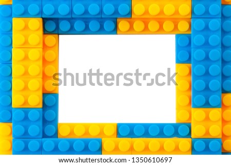 Educational toy and kindergarten toys concept theme with a blue and yellow frame made of plastic building brick blocks with the middle left blank and copy space