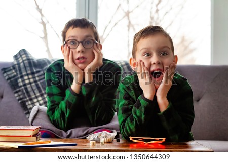 surprised kids on the couch watching tv. the children opened their mouths in shock Royalty-Free Stock Photo #1350644309