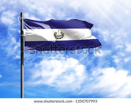 National flag of El Salvador on a flagpole in front of blue sky.