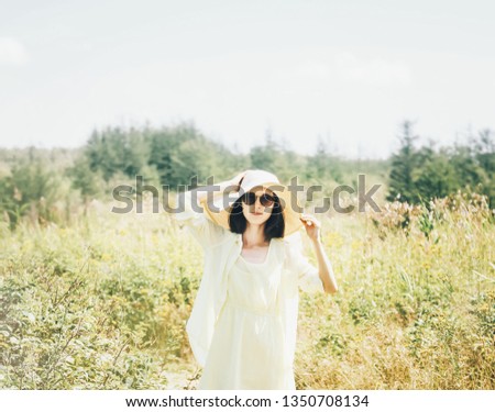 Summer stylish young woman in hat and sunglasses walking on sunny day outdoor.