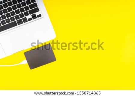 Laptop keyboard, storage drive or hard disk on yellow background with selective focus and crop fragment. Business, backup and copy space concept.