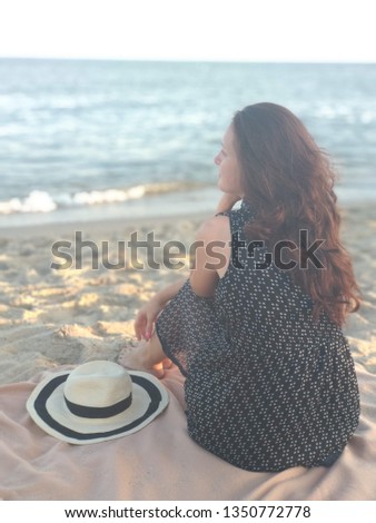 Girl sitting on the beach with hat and looking on the sea