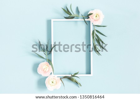 Flowers composition. White flowers, eucalyptus leaves, photo frame on pastel blue background. Flat lay, top view, copy space