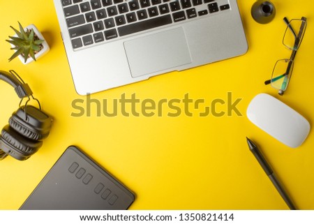 Top view of the workplace designer. Creative designer, graphics tablet, laptop, and accessories for the graphic designer.Flat lay.On yellow background