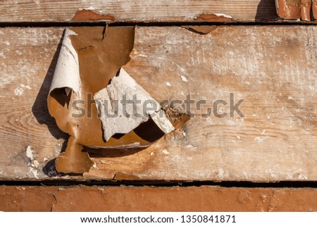 Peeling brown paint on a wooden wall close-up.