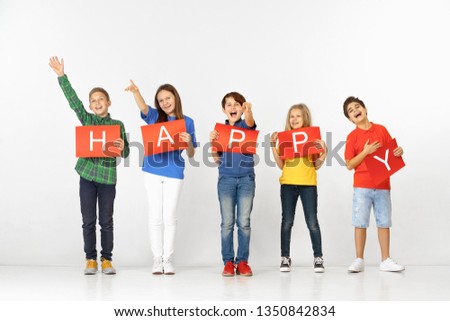 Friendship make us better. Group of happy smiling children with red banners making word isolated in white studio background. Education and advertising concept.