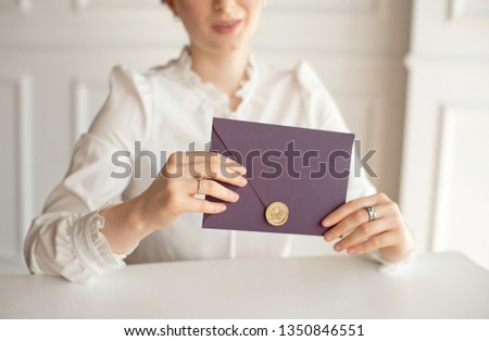 Close-up woman with slim body holding in hands the invitation card purple color square shape envelope card