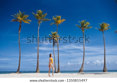 Beautiful woman in full growth on the sand and high palm rest tropics                           