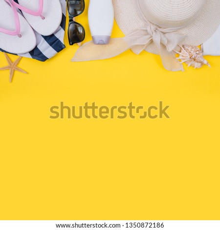 Beach flat lay accessories. Sun hat, beige towel, yellow cosmetic bag, camera, cream, sunscreen bottle, comb and seashells. Summer travel holiday concept