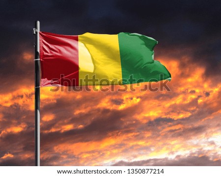 flag of Guinea on flagpole fluttering in the wind against a colorful sunset sky