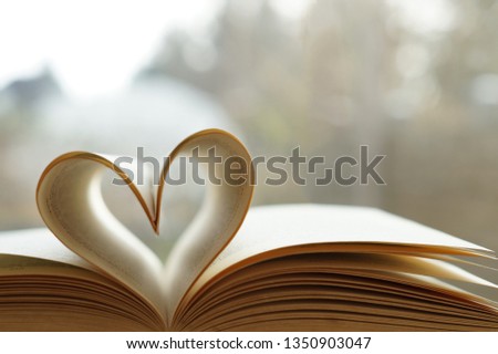Heart from page of book for valentine's day concept with blurred bright light background and vintage tone.