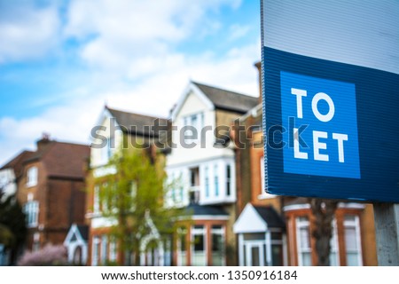 Estate agency 'To Let' sign board with large typical British houses in the background Royalty-Free Stock Photo #1350916184