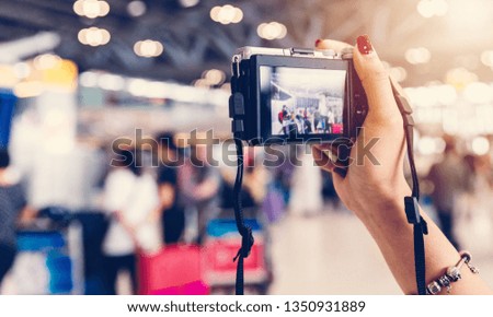 close up of female hand holding DSLR digital camera among the crowd at airport

