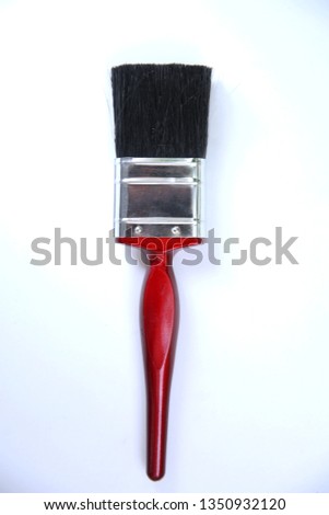 Paint brush with red handle is lay on white background