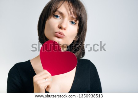 beautiful business woman with a paper heart in hands isolated on gray background