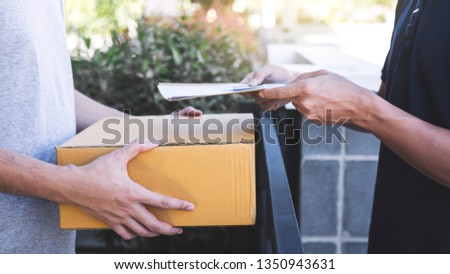 Delivery mail man giving parcel box to recipient and signature form, Young owner signing receipt of delivery package from post shipment courier, Home delivery service and working with service mind.