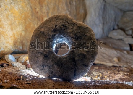 stone wheel in a cave illuminated by counter light Royalty-Free Stock Photo #1350955310