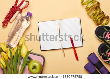 Female fitness still life. Sport accessories, tulips flowers and scales on a yellow background. Mockup. Planning of diet and trainings. Top view with copy space. Healthy lifestyle concept. Slimming