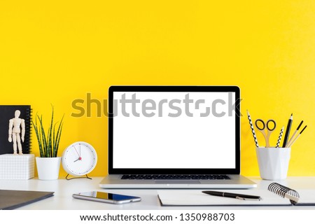 Desk, laptop and school supplies over the yellow background. Education, studying and back to school concept Creative desk with yellow wall and stationery. Mock up.
