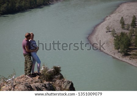 The pair stands high among the mountains and clouds and the mountain river. man and woman are in love and happy