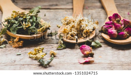 Aromatic flowers tea in spoons on rustic wooden background