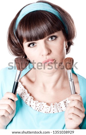 Portrait of attractive brunet woman in blue dress with two make-up brushes isolated on white background