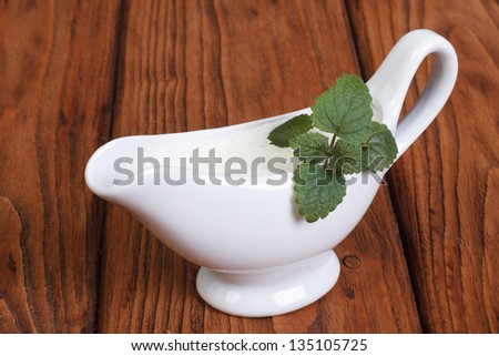 White bechamel with mint leaves on a wooden surface