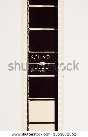 Extreme close up of 35mm movie film strip with picture start text message on frame