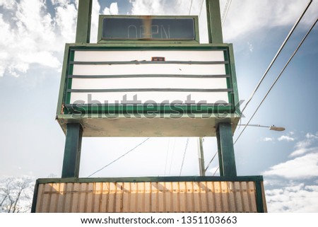 An old, dirty and empty backlit box letter sign board standing on the roadside.