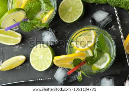 Mojito cocktail in a glass glass with lime, mint and lemon and bar accessories on a dark concrete background. make a mojito.