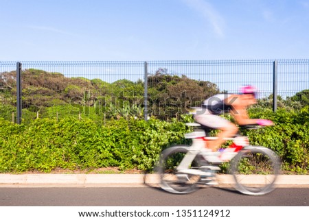 Athlete cycling motion speed blur close-up action morning road course second leg of triathlon race.