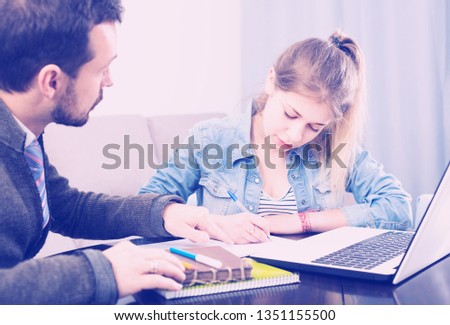 Young italian positive tutor explaining material to his female client at home
